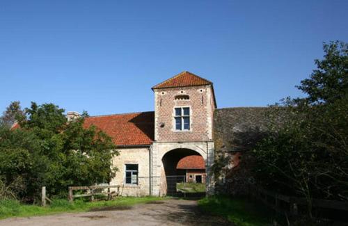 an old stone building with a tower and a gate at B&B Kraneveld in Haacht