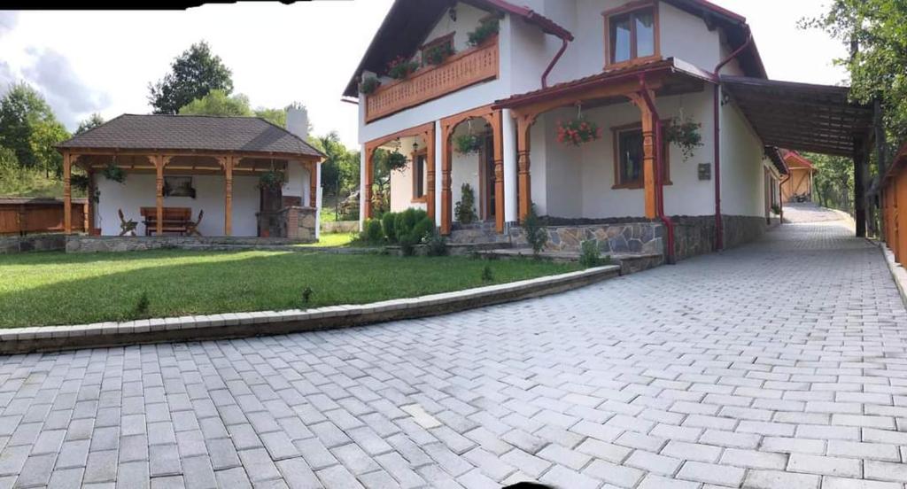 een huis met een stenen oprit en een tuinhuisje bij Casa pintioi in Ieud