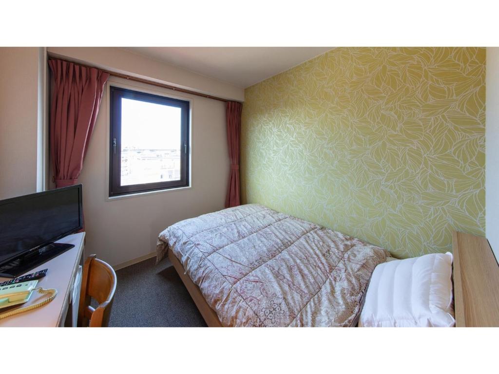 a small bedroom with a bed and a window at Matto Terminal Hotel - Vacation STAY 98876v in Hakusan