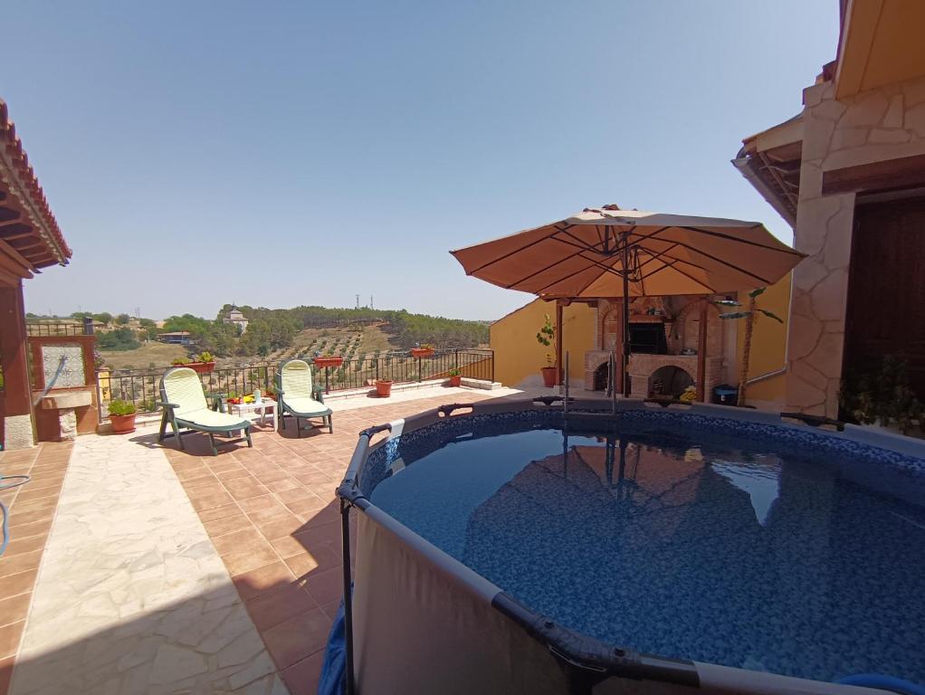 einen Pool mit einem Sonnenschirm und einer Terrasse in der Unterkunft Casa de la Abuela Pili in Colmenar de Oreja