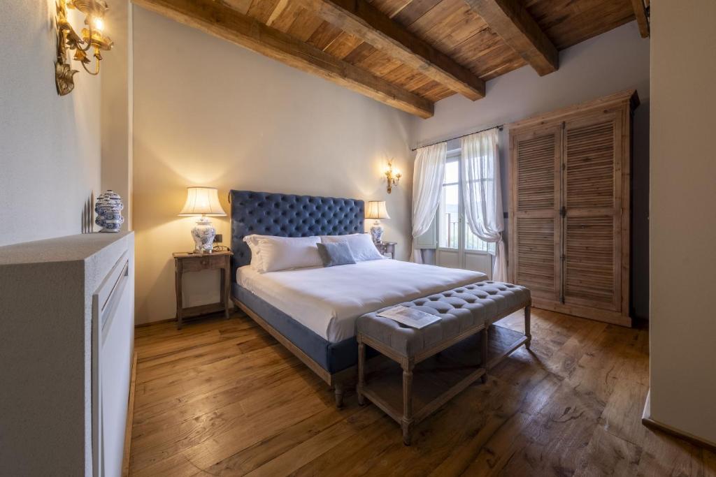 een slaapkamer met een kingsize bed en een houten vloer bij Tenuta Bussia - Wine Relais & Spa in Monforte dʼAlba