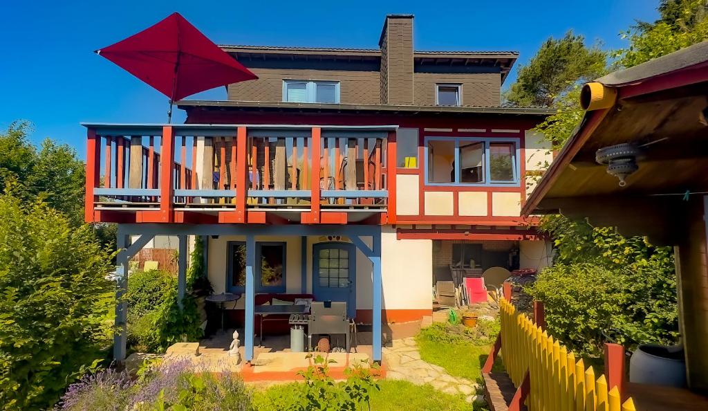 a house with a large deck with a red umbrella at Wie im Himmel in Hatzfeld