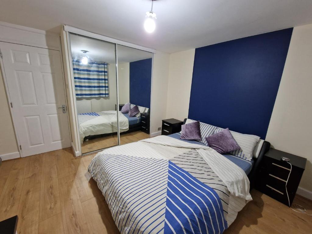 1 dormitorio con 1 cama con pared azul y espejo en Rooms Shared Kitchen FREE Parking, en Slough