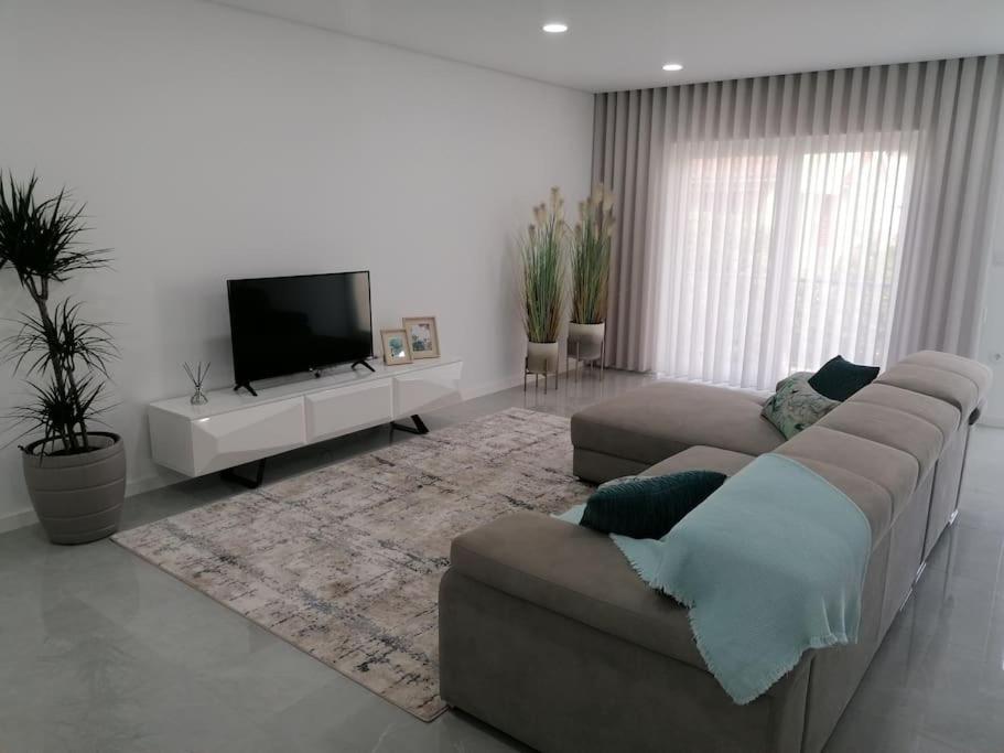 ein Wohnzimmer mit einem Sofa und einem Flachbild-TV in der Unterkunft Alojamento familia Carvalhais in Ponte de Vagos