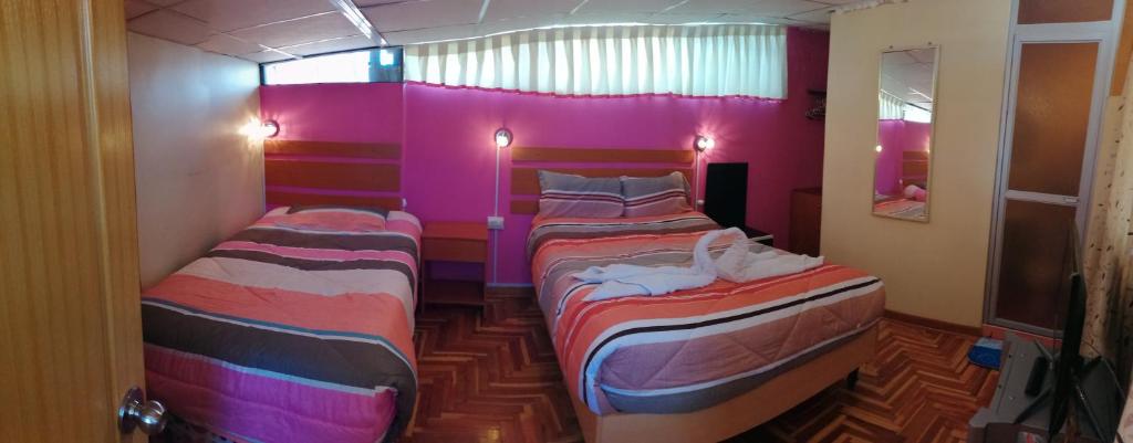 2 Betten in einem Zimmer mit rosa Wänden in der Unterkunft Naty's Guest House in Cusco