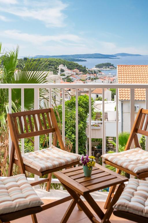 balkon z 2 krzesłami i stołem z kwiatami w obiekcie Maki Apartments w Hvarze