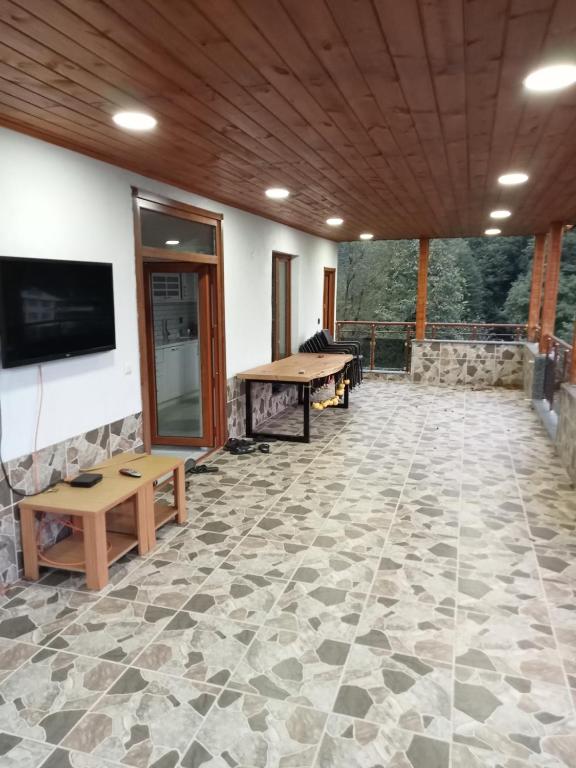 a screened porch with a stone floor and a flat screen tv at Kulaksız Köşk Villa in Rize