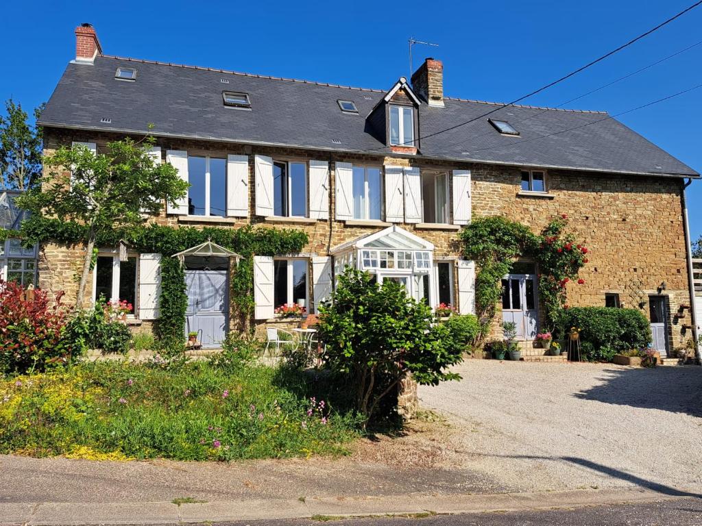 een groot bakstenen huis met witte deuren en ramen bij La Paix, Gîte bucolique en Normandie in Condé-sur-Noireau