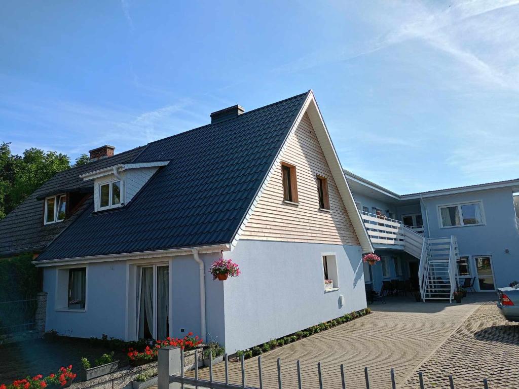 une maison blanche avec un toit noir dans l'établissement Rybacki Domek 50 metrów do morza!, à Dziwnów