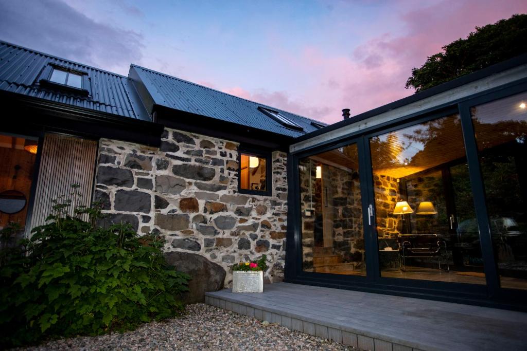 a stone house with glass doors and a patio at The Woods at Whitepark Bay in Ballintoy