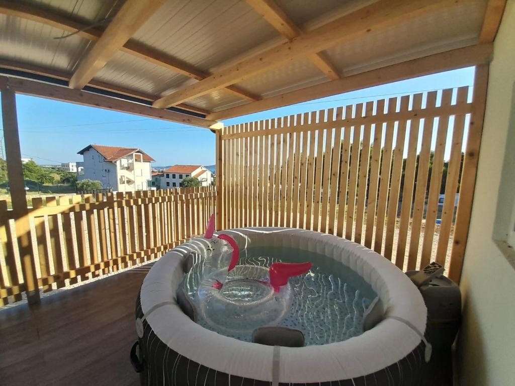 a hot tub on a deck with a wooden fence at Tiny House Lily with jacuzzi in Sveti Filip i Jakov