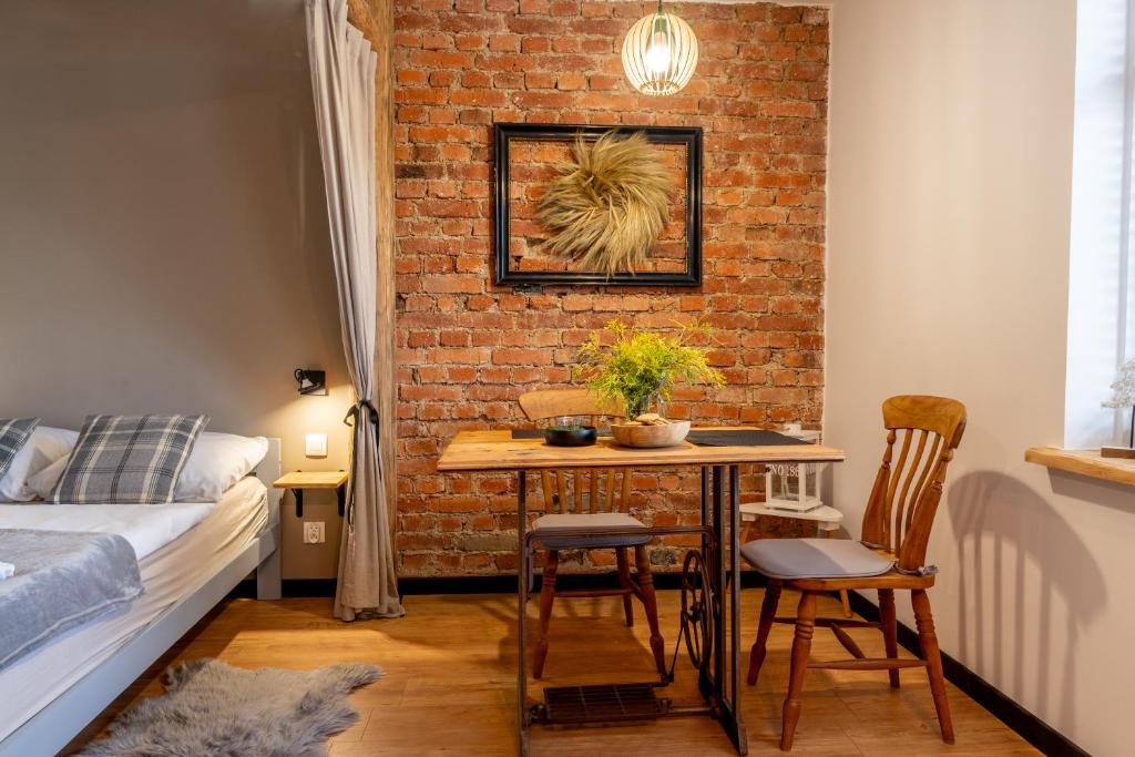 Zimmer mit einem Tisch und einer Ziegelwand in der Unterkunft Apartamenty sudeckie nad zalewem IV in Sosnowka