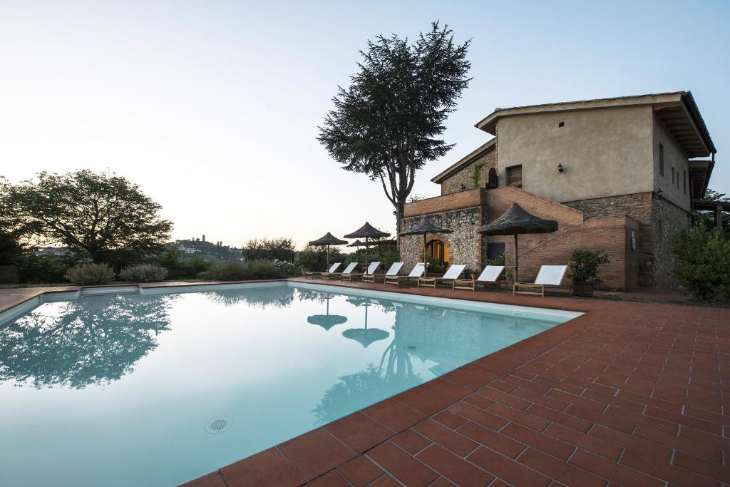a swimming pool in front of a house at Agriturismo I Pini in San Gimignano