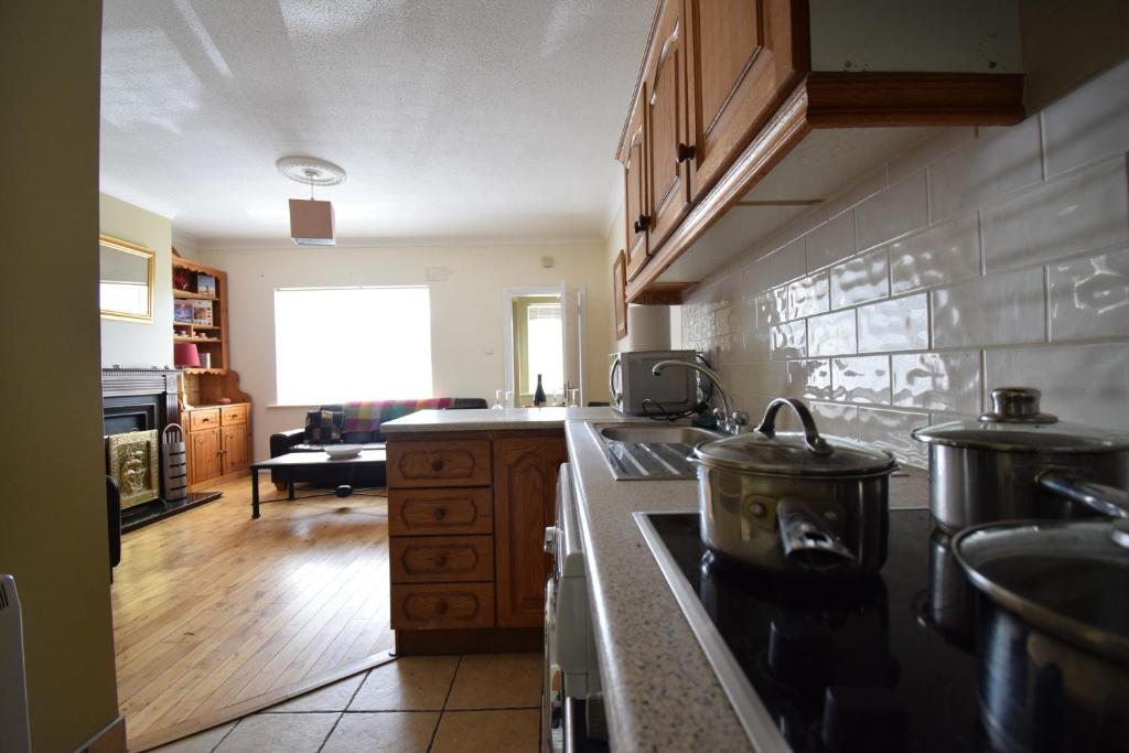 a kitchen with a stove top oven next to a living room at 27 Cill Ard Bohermore galway in Galway