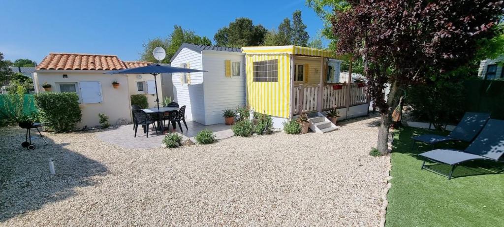 a small backyard with a yellow building next to a house at Bungalow dans résidence privée in Dolus-d'Oléron
