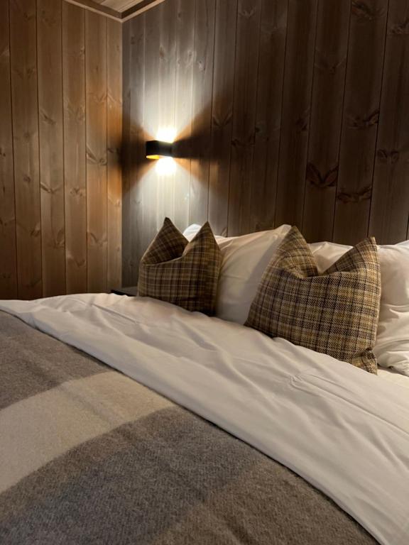 łóżko z poduszkami i lampką na ścianie w obiekcie Sogndal Chalet w mieście Sogndal