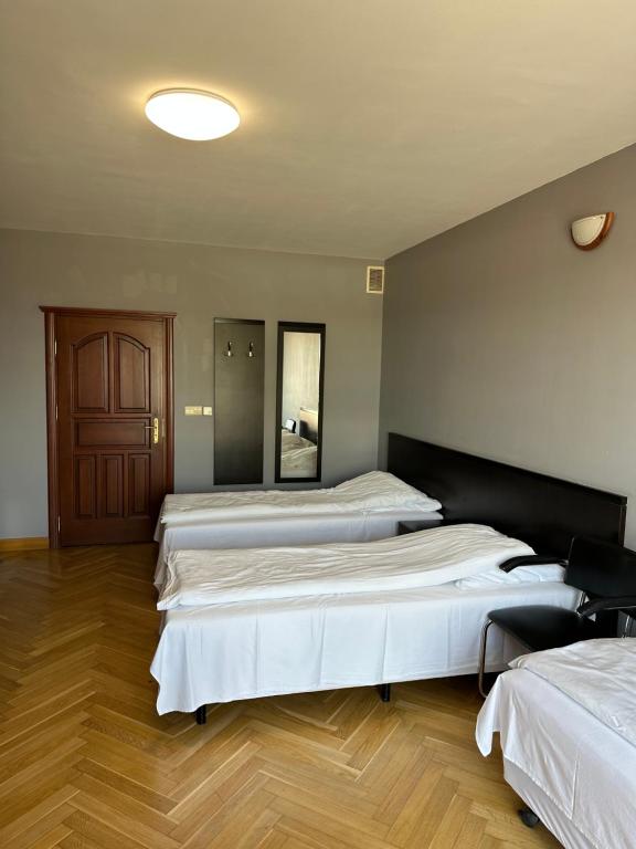a room with three beds in it with wooden floors at Pokoje Komfort in Szypliszki