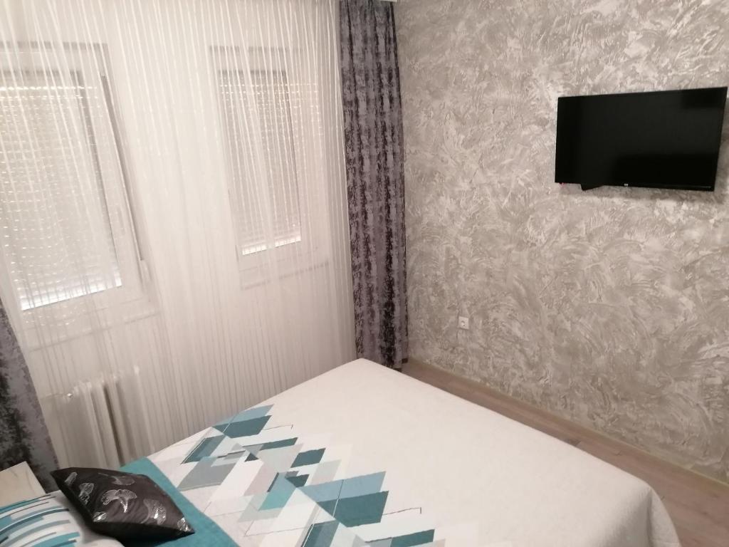 a bedroom with a bed and a tv on a wall at JM Apartman in Čačak