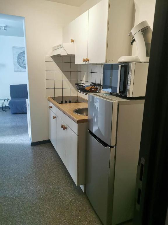 a small kitchen with white cabinets and a microwave at Impasse 1 in Fosses-La-Ville