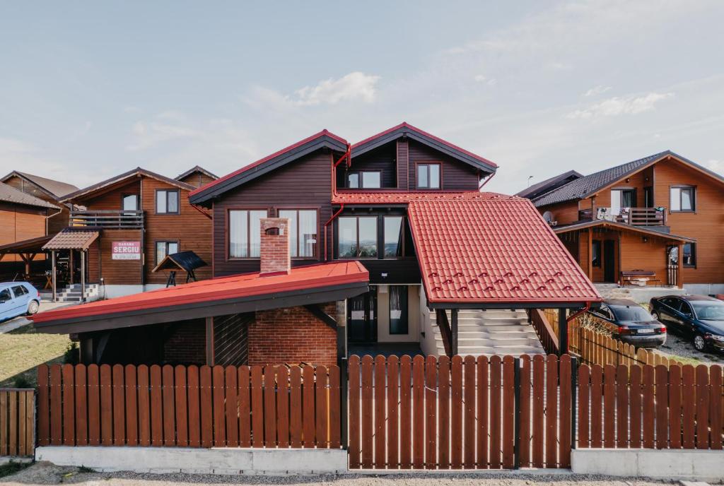 une maison avec un toit rouge derrière une clôture dans l'établissement Pensiunea Suzanne Băile Figa, à Beclean