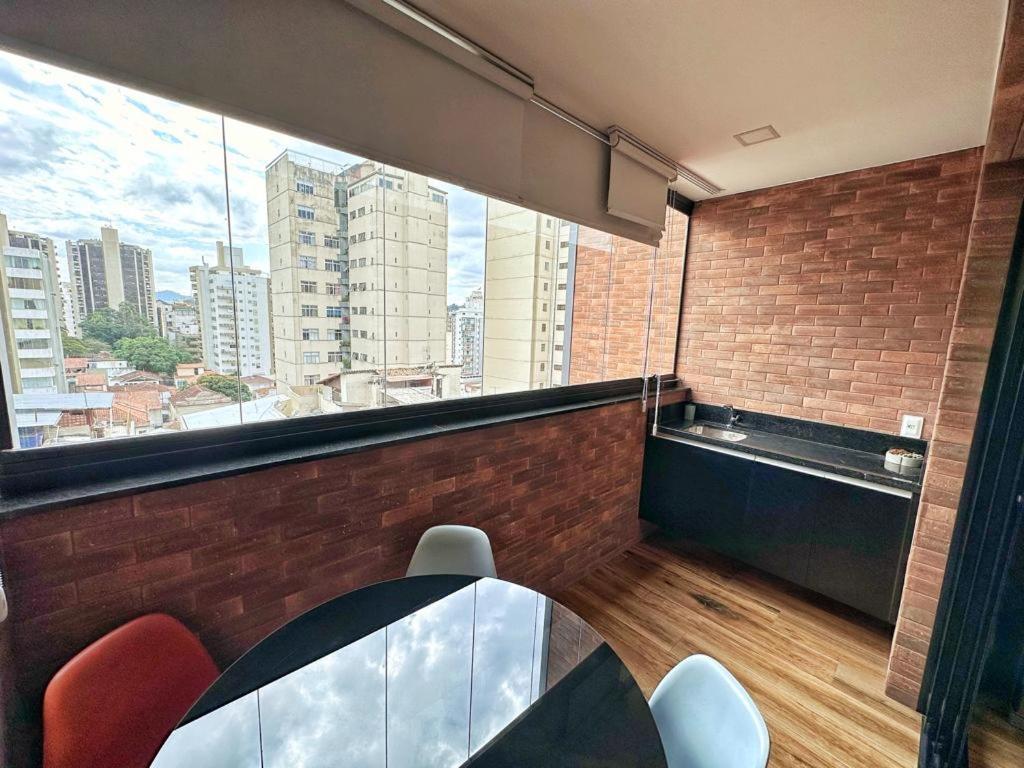 a room with a table and chairs and a large window at STUDIO COMPLETO - CENTRO - Com GARAGEM in Juiz de Fora