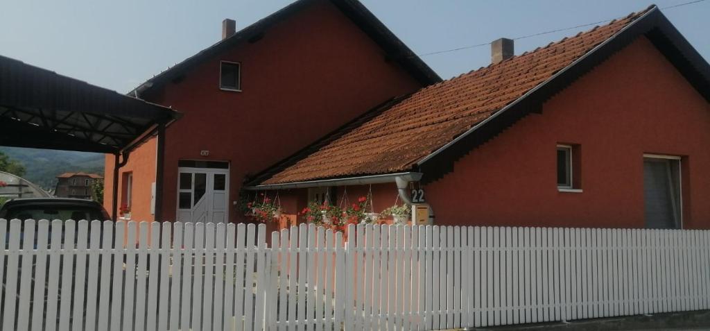 a red house with a white fence in front of it at Apartman Mitrovići Bajina Bašta in Bajina Bašta