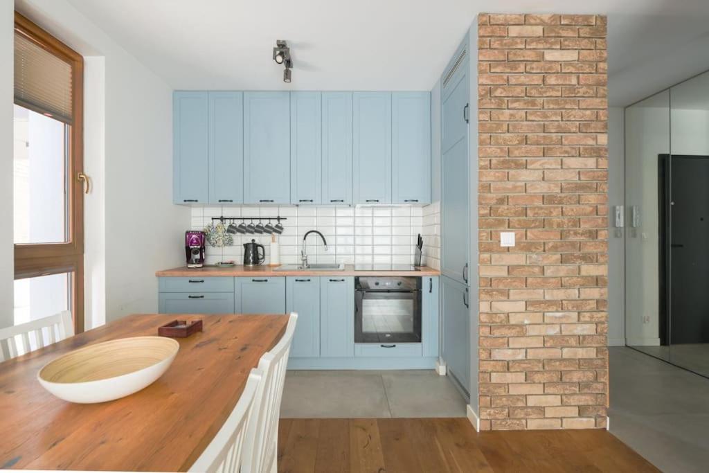 a kitchen with blue cabinets and a brick wall at Front Park by Q4Apartments in Gdańsk