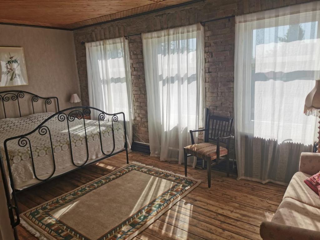 a bedroom with a bed and a chair and windows at Rynge teaters boningshus in Ystad