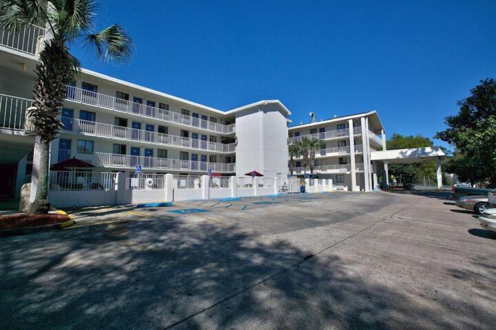 a large white building with a palm tree in front of it at Loyalty Inn Tallahassee in Tallahassee