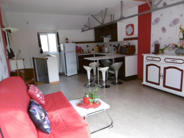 a living room with a red couch and a kitchen at Gîte du Moulin in Saint-Julien-sur-Cher