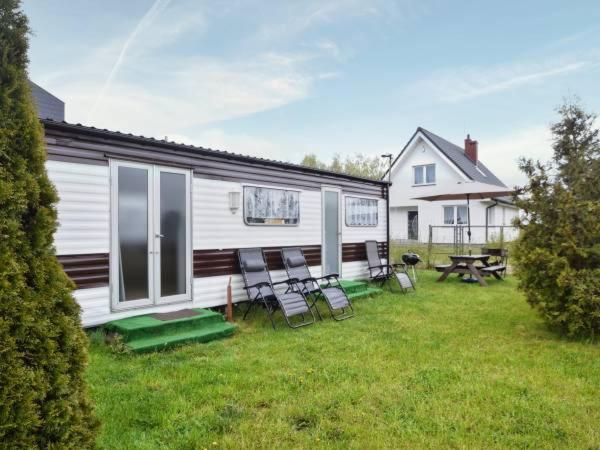 a house with chairs and a picnic table in the yard at Domek Holenderski in Mielno