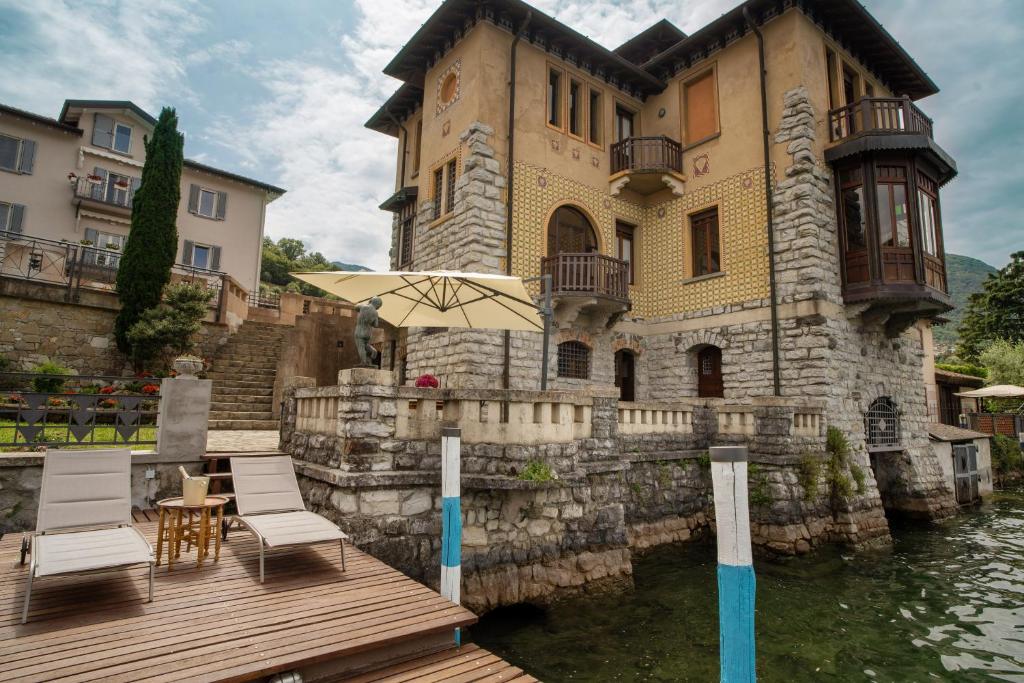 une maison avec un quai en bois, des chaises et un parasol dans l'établissement Villa Cecilia - pieds dans l'eau, à Sulzano