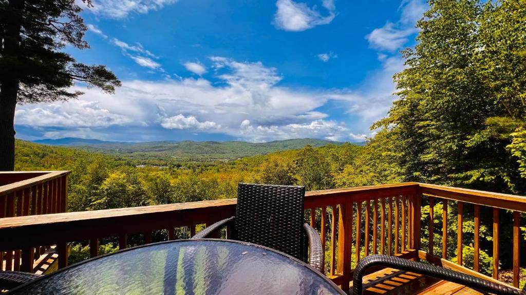a table and chairs on a deck with a view of the mountains at Waking up in the Nature in Campton