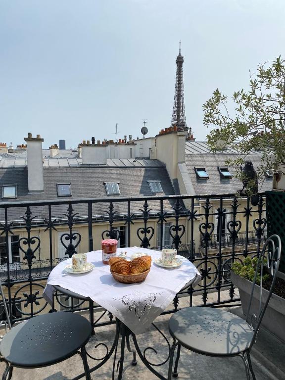 Una mesa con cestas de comida en un balcón con la Torre Eiffel. en Chaillot - Lübeck I 1bdr by B'Your Home, en París