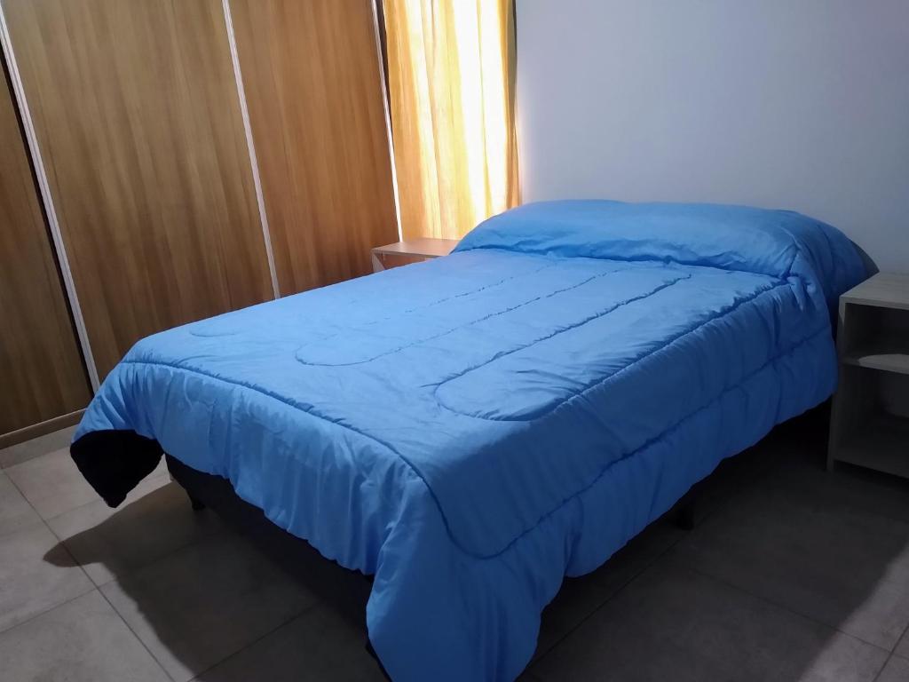 a bed with a blue blanket on top of it at Antonia in Guaymallen