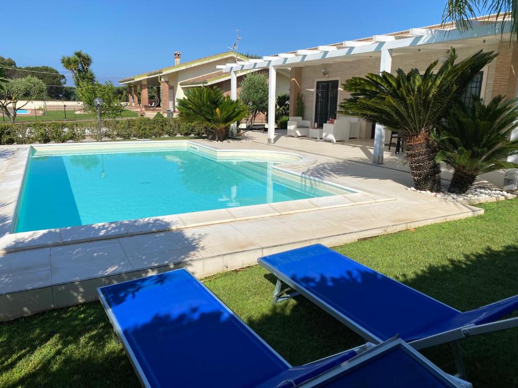 una piscina con 2 sillas azules frente a una casa en Alloggio turistico Villa Camelia Lavinio en Anzio
