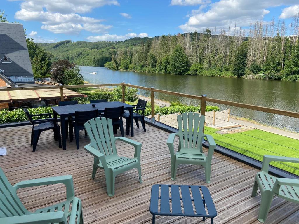 een terras met een tafel en stoelen en uitzicht op een rivier bij La Villa Wellness in Hastière-par-delà