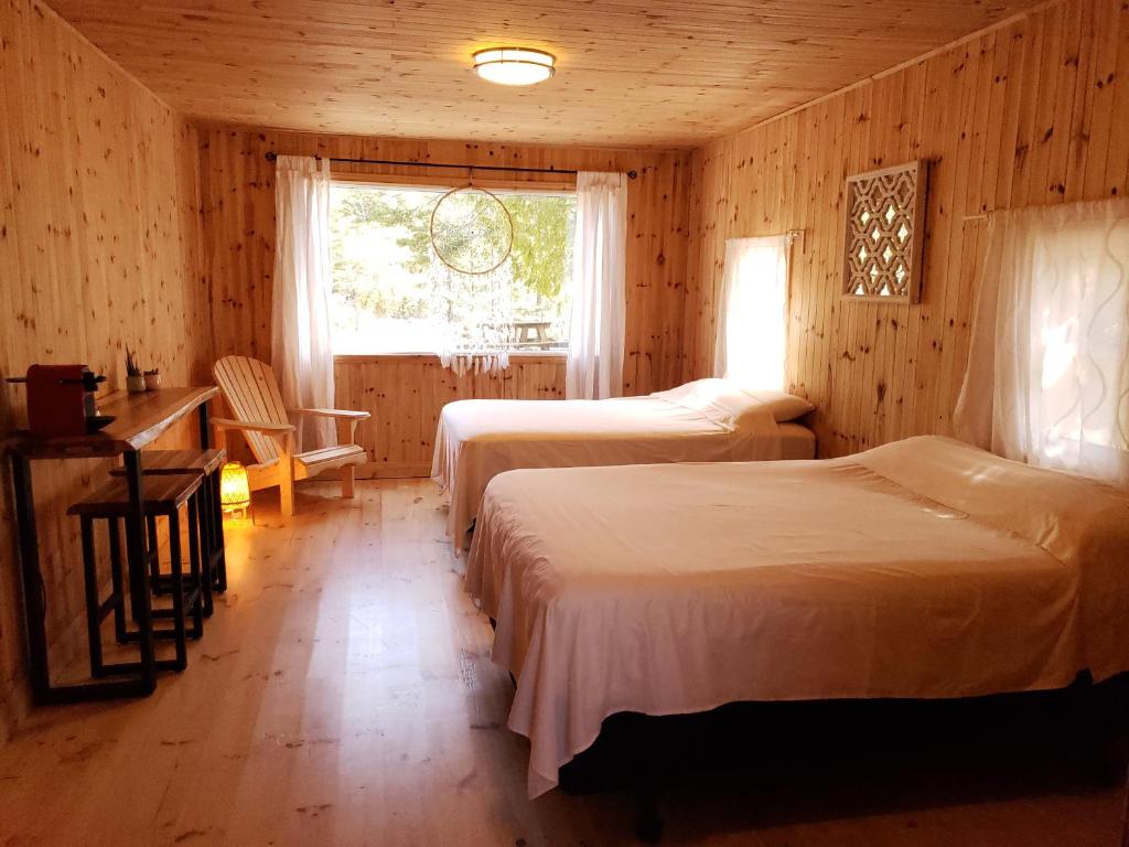 um quarto com 2 camas, uma secretária e uma janela em New Buddha Bing Unique Experience Cottage and Cabins em Tobermory