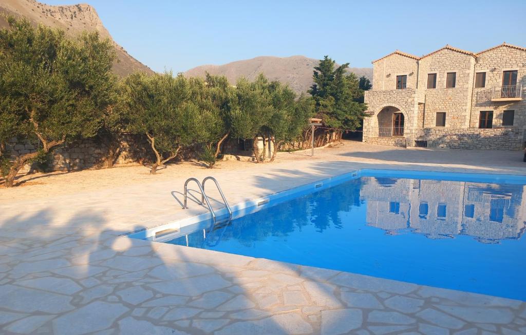 a swimming pool in front of a house with a building at Koukouri Suites in Areopoli