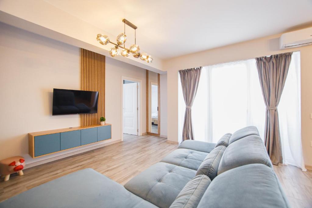 a living room with a blue couch and a tv at Charming Family Haven in Oradea