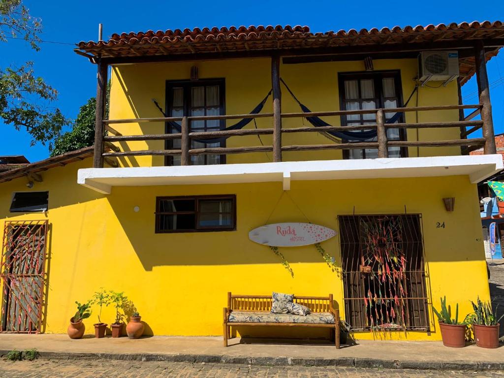 un gato sentado en un banco frente a un edificio amarillo en Rudá Hostel, en Itacaré