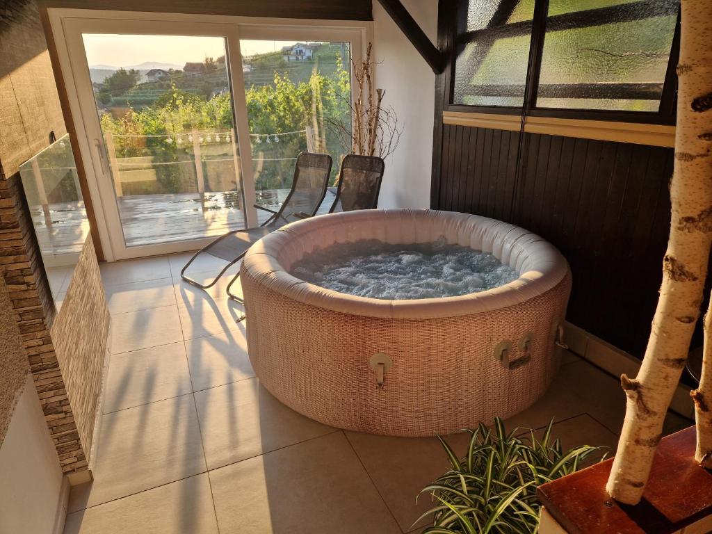 een groot bad op een patio met 2 stoelen bij Vineyard Holidays Cottage with Jacuzzi in Metlika