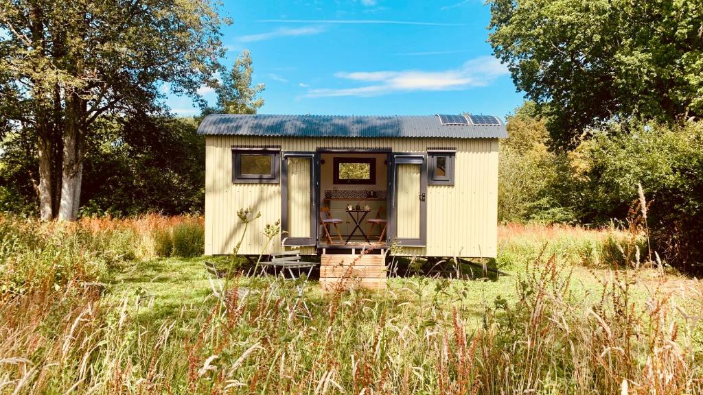 an old shed sitting in a field of grass at Apple Orchard Shepherd Huts in Staple Cross