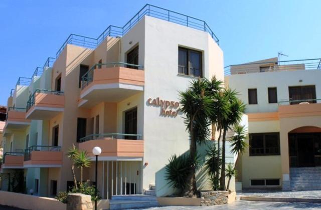 a large white building with palm trees in front of it at Calypso Hotel Apartments in Kato Daratso