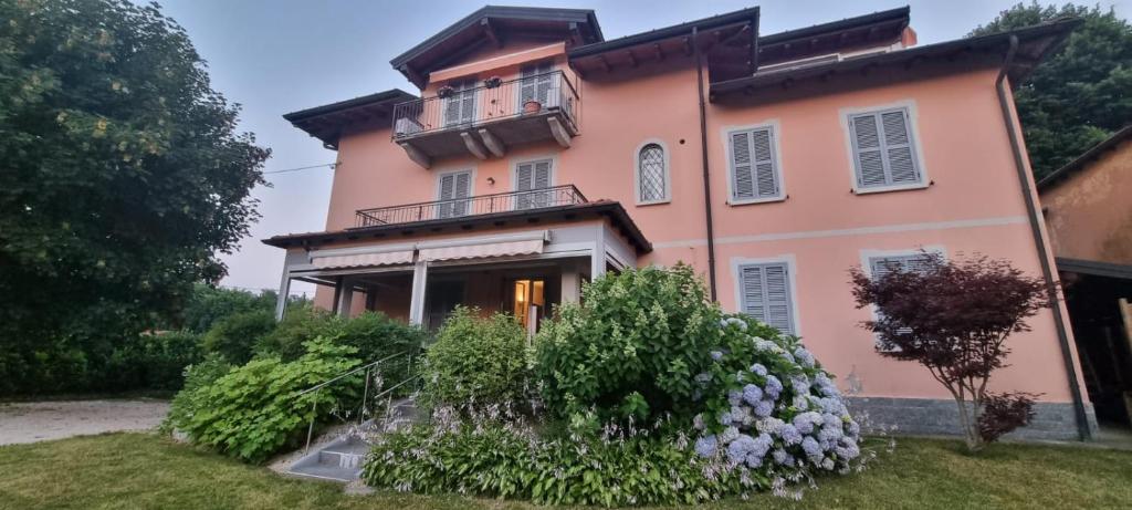 a large pink house with a balcony and flowers at LA MAISON ROSE in Leggiuno
