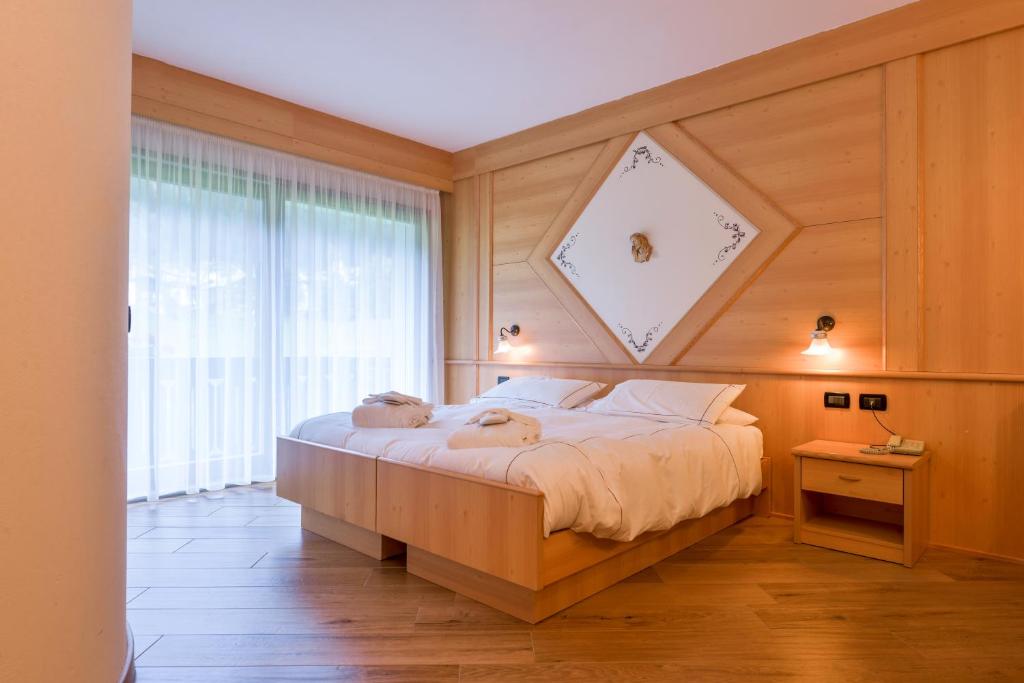 a bedroom with a large bed with a large window at Chalet Pineta relax location in Canazei