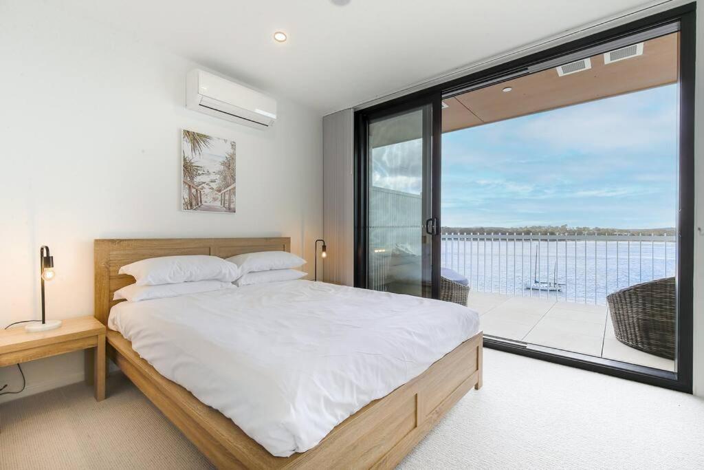 a bedroom with a large bed and a large window at OHANA - SeaHome in Batemans Bay
