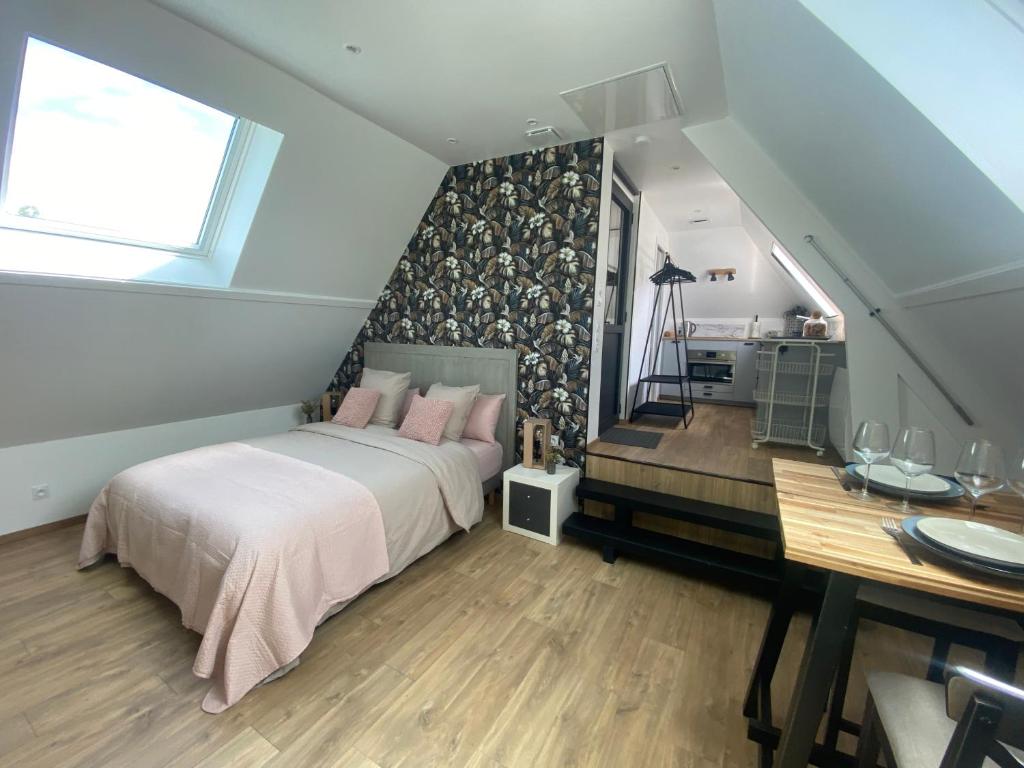 Un dormitorio con una cama con almohadas rosas y una mesa. en Appartement entre terre et mer à proximité de Honfleur, en Équemauville