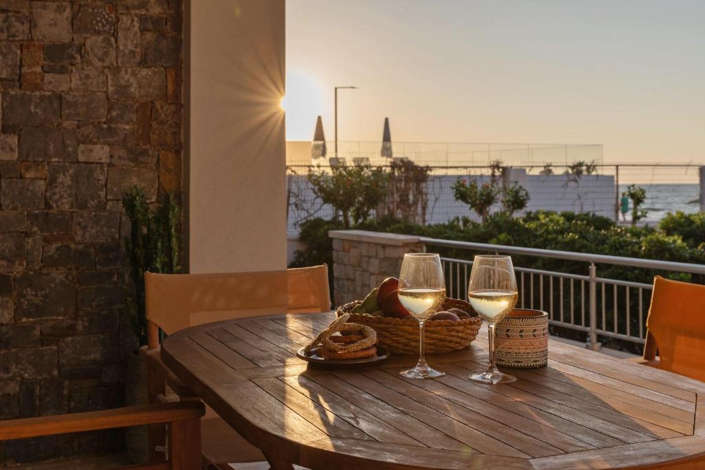 een houten tafel met twee wijnglazen en een broodmand bij Aelia seafront house in Kokkíni Khánion