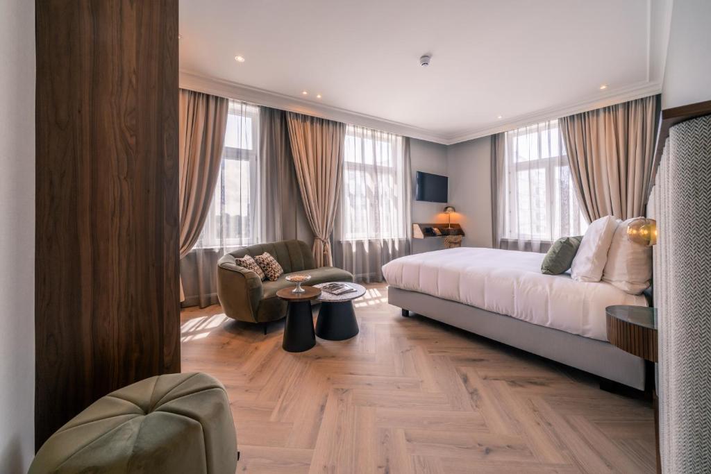Hotel Du Parc في أوستند: غرفة نوم بسرير واريكة وكرسي